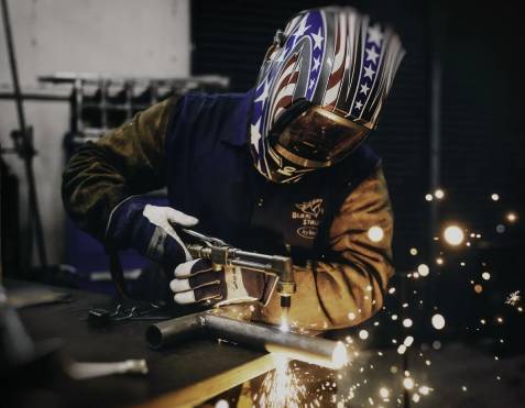 A worker welding a piece of metal rod