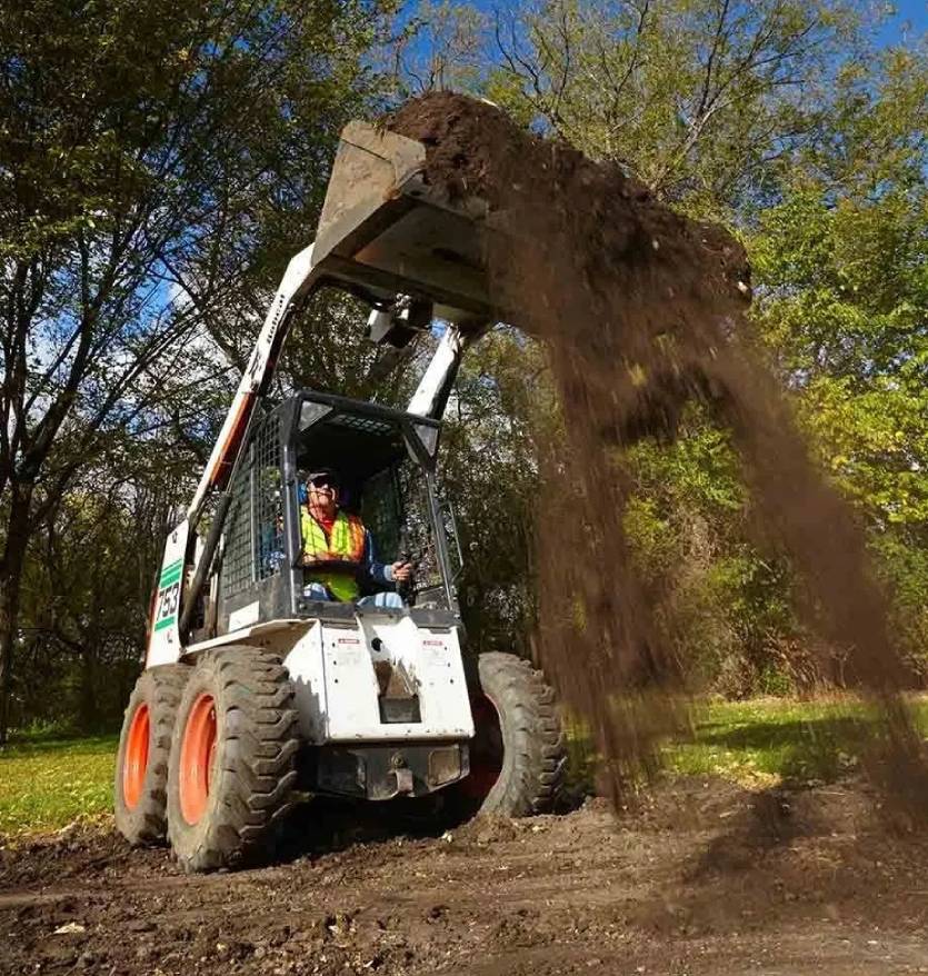 A man operating an earth mover to lift sand