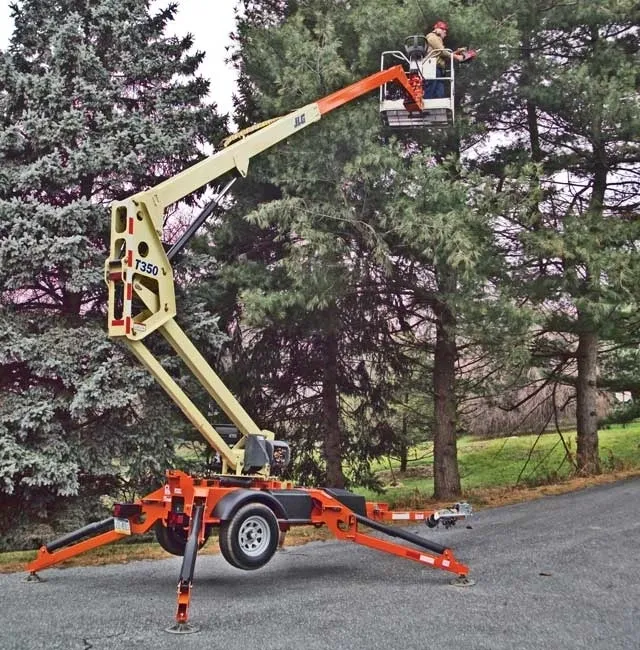 A man using a towable boom lift to prune trees